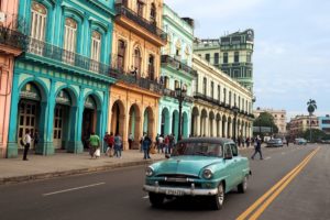 Car driving in front of colourful buildings in Cuba