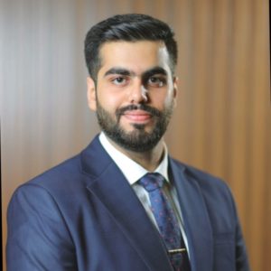 Headshot of Shivam Nagal smiling in a blue suit and tie